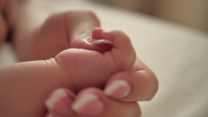 A close up of a mother's hand holding her newborn baby's hand.