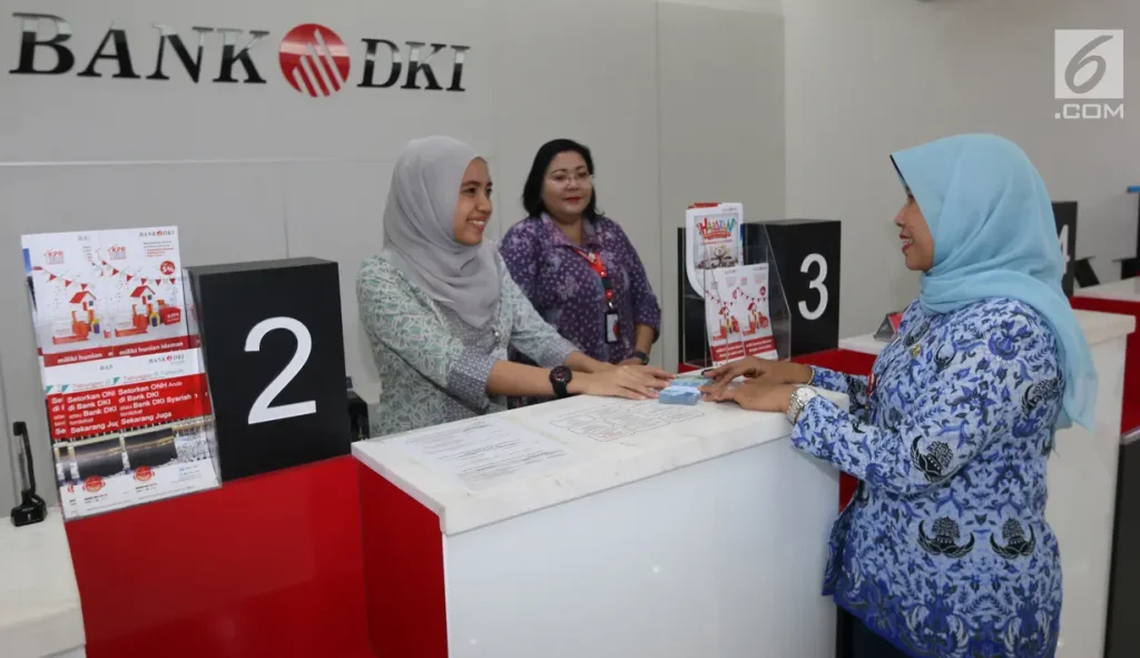 A teller at a Bank DKI branch in Indonesia is assisting a customer with a transaction.