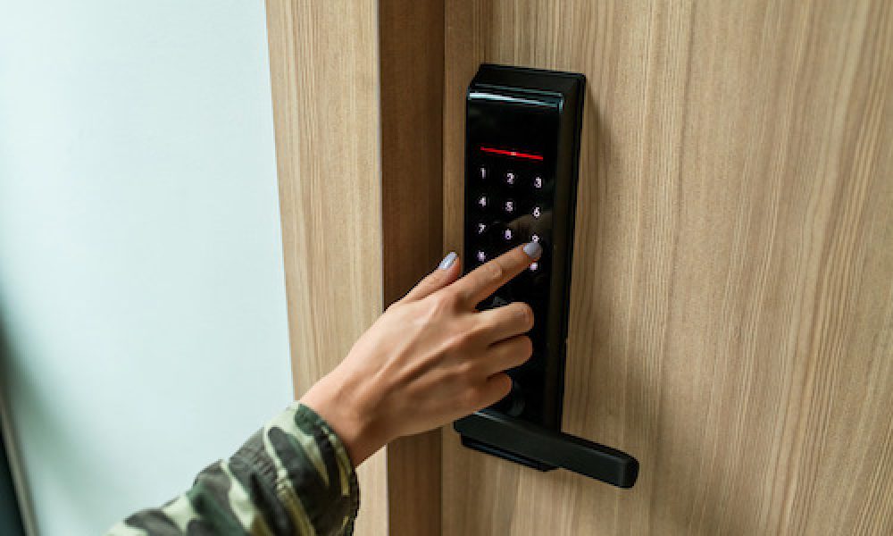 A person is using a keypad to lock a door. The image is about how to lock a photo gallery on an iPhone.