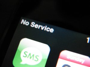 A close-up of an iPhone with the 'No Service' error message displayed on the screen.