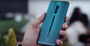 The image shows a hand holding an Oppo Reno smartphone, which has NFC capabilities, is affordable, has good specifications, a reliable processor, sufficient storage capacity, and a long battery life.