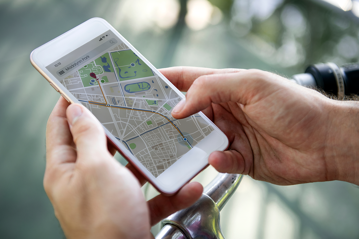 A person holding a smartphone and using a map app to track the location of a lost phone using its IMEI number.